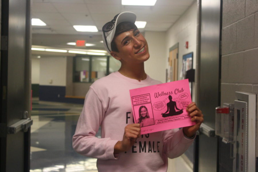 Sophomore Lucas Lowry is holding one of the posters for the Wellness Club.